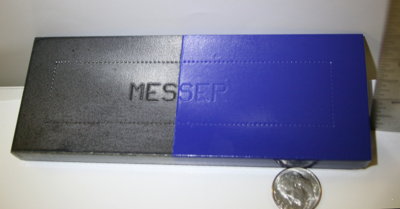 An example of marking on a block consisting of two different types of material. Evenly-spaced dots create a rectangular frame across both materials, at the center of which “Messer” is inscribed in all-capital letters.